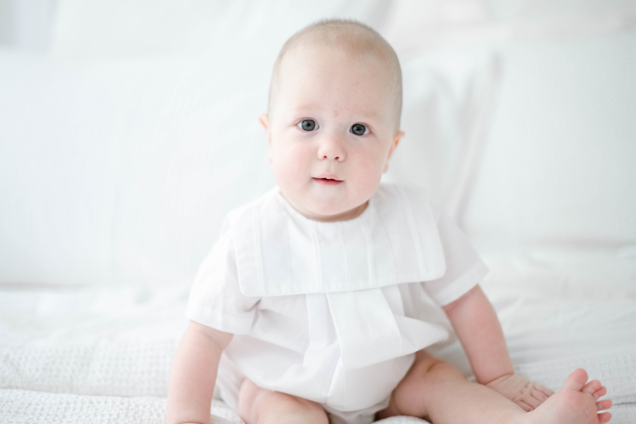 infant boy smiles at camera in portrait with natural light taken indoors 